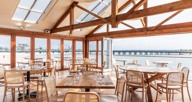 View of indoor restaurant tables overlooking the water and Barwon Heads Jetty