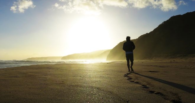 Young man walking along Johnna beach alone at sunset